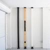 Three wooden poles with black bases leaning against a white brick wall.