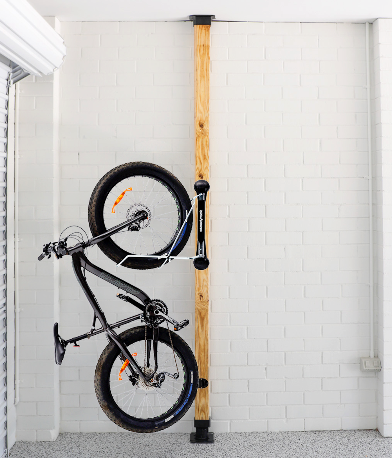 Bicycle installed on a wooden post against a white brick wall.